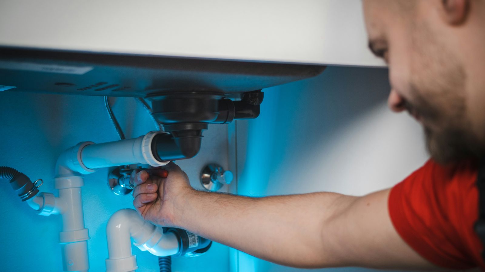 Plumber fitting pipework under a kitchen sink